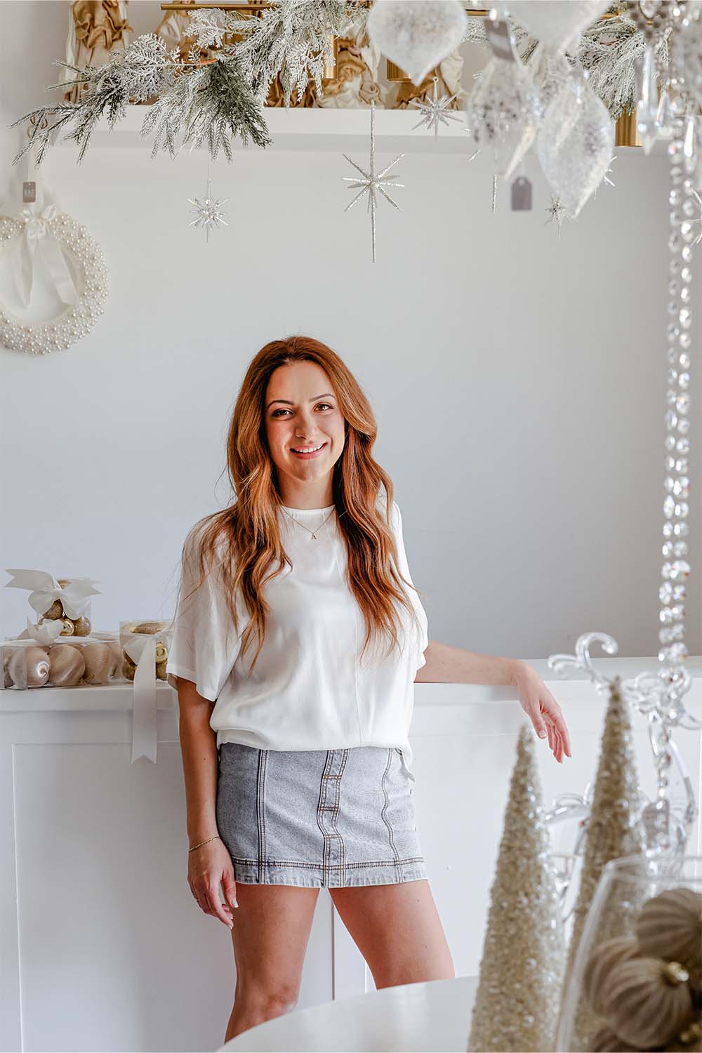 Woman in white top and skirt beside elegant white and gold christmas decorations, luxury christmas decor and tree decorations Sydney.