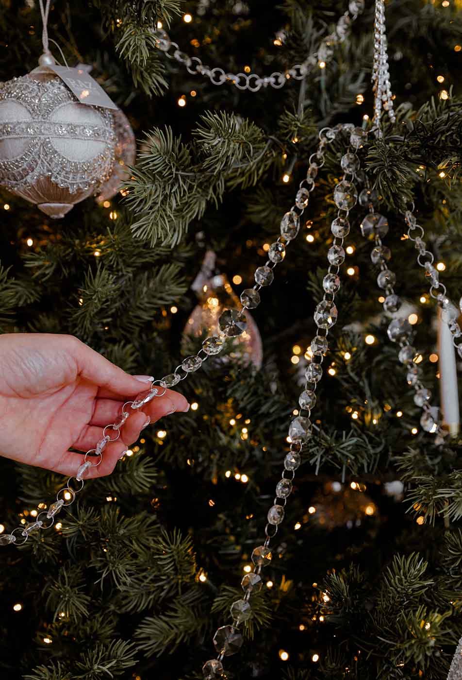 Hand placing crystal garland on luxury Christmas tree with elegant ornaments by Christmas Decorators Sydney, Dancer and Dasher.