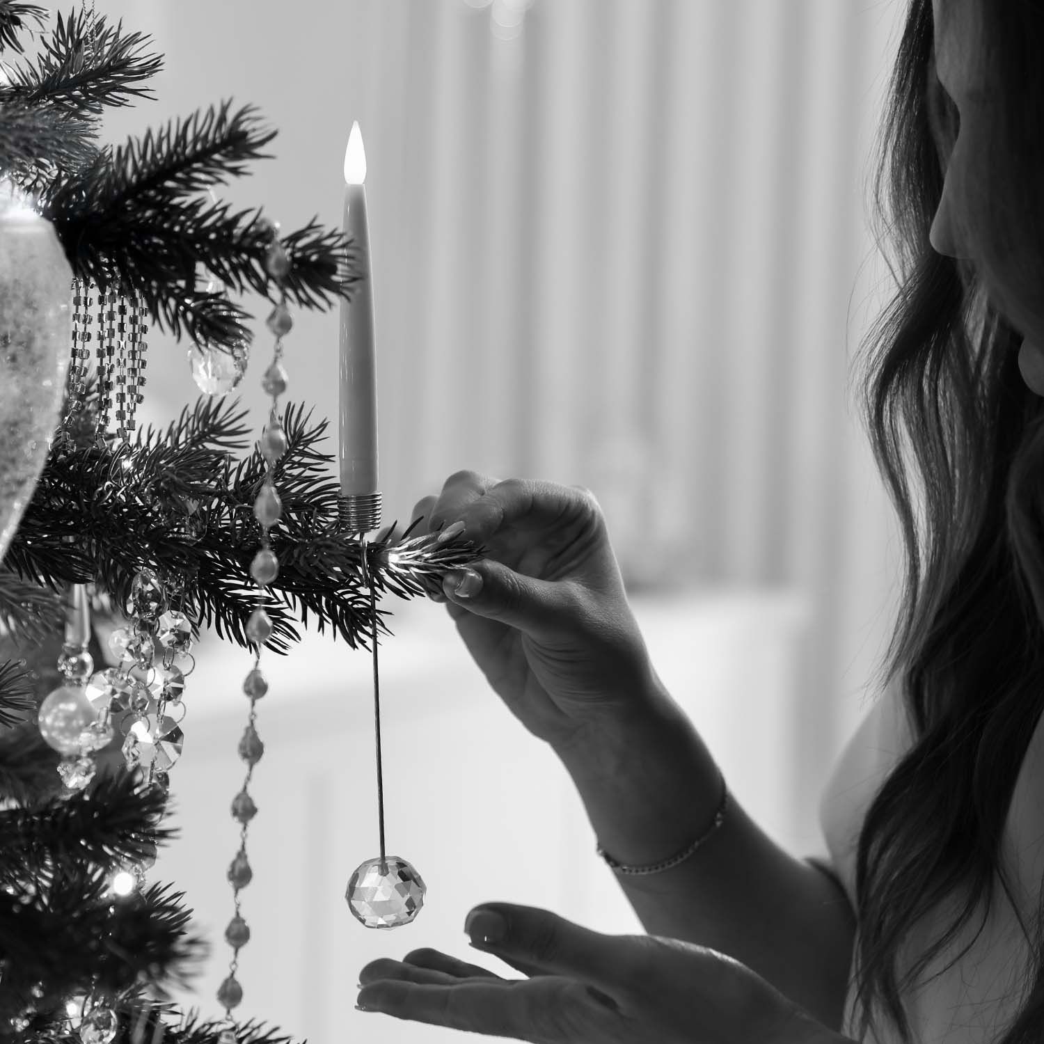 Hand decorating Christmas tree with candle and crystal ornament, luxury christmas store Sydney with christmas tree candles and garlands.
