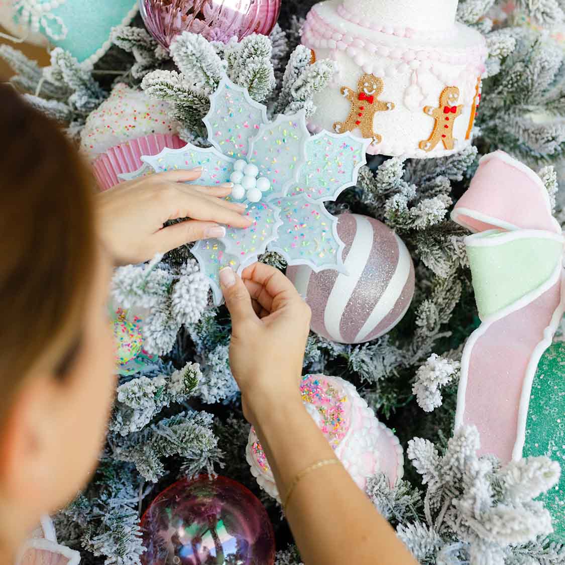 Hands adjusting blue holly ornament on pre dressed christmas tree, featuring stylish christmas tree design and christmas decorations pack.