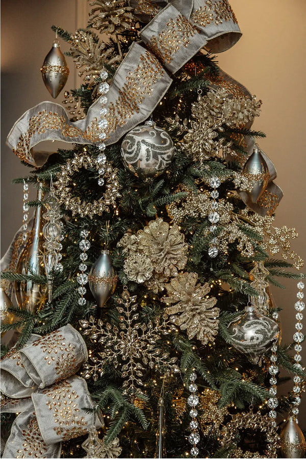 Close-up view of the "Peace on Earth Christmas Tree" showcasing its intricate ornaments, including amber crystal snowflakes, golden pinecones, and shimmering ribbons.