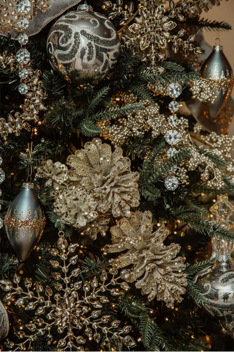 A detailed view of the Christmas tree decorations, highlighting the diamond bead garland, dark grey scroll baubles, and sparkling amber crystal accents.