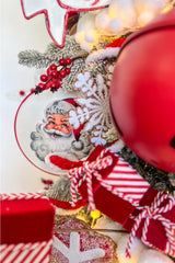 A festive Christmas scene featuring a Santa Claus illustration on a plate, surrounded by candy canes, a gingerbread man ornament, and red berries against a backdrop of white snowflakes.