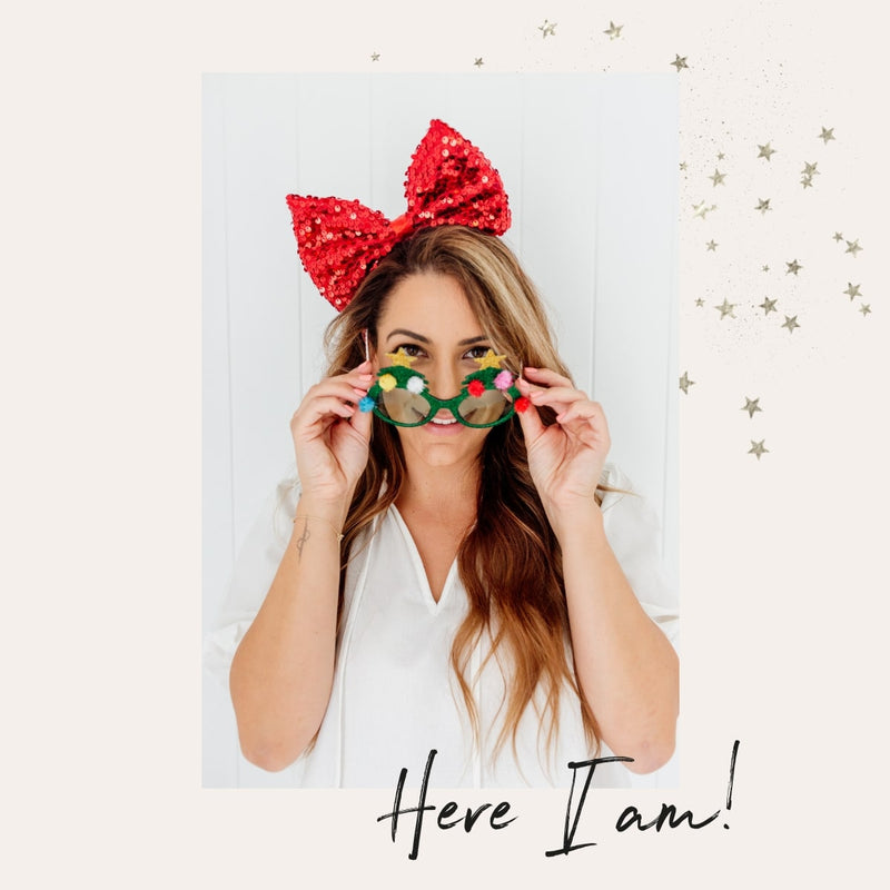 Dancer & Dasher Founder Alana portrait image wearing a sequenced Christmas bow and Christmas Tree glasses text overlayed on top displaying "Here I am"
