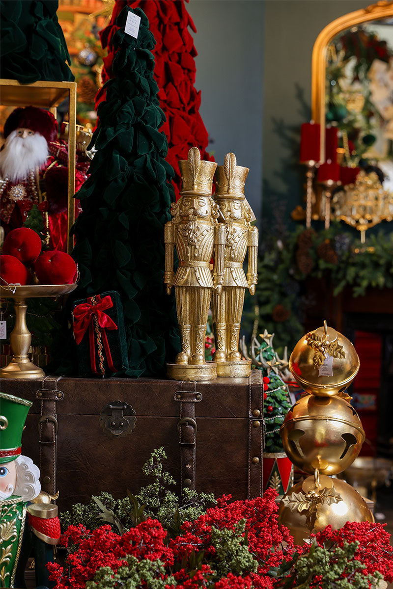 Gold nutcracker figurines on a vintage timber chest beside a green cone tree in the Sydney Christmas boutique